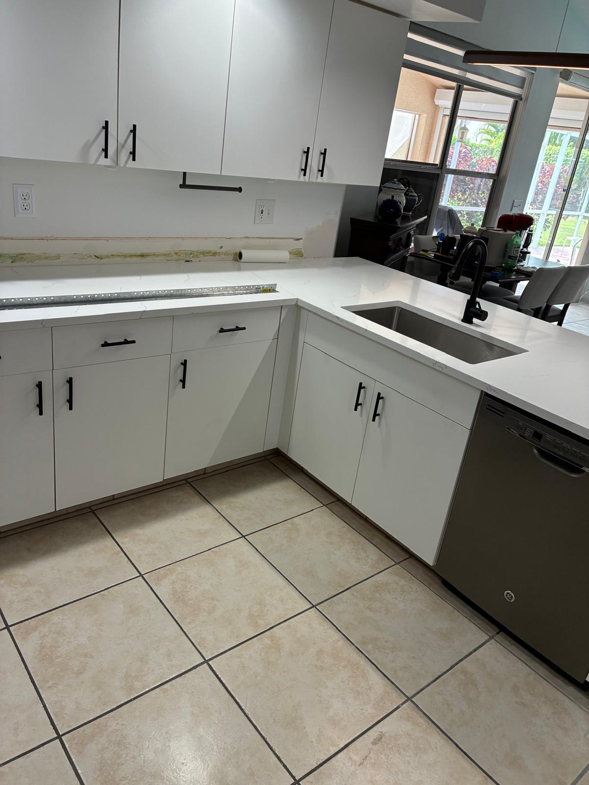 White flat-panel cabinets with quartz countertops and black hardware