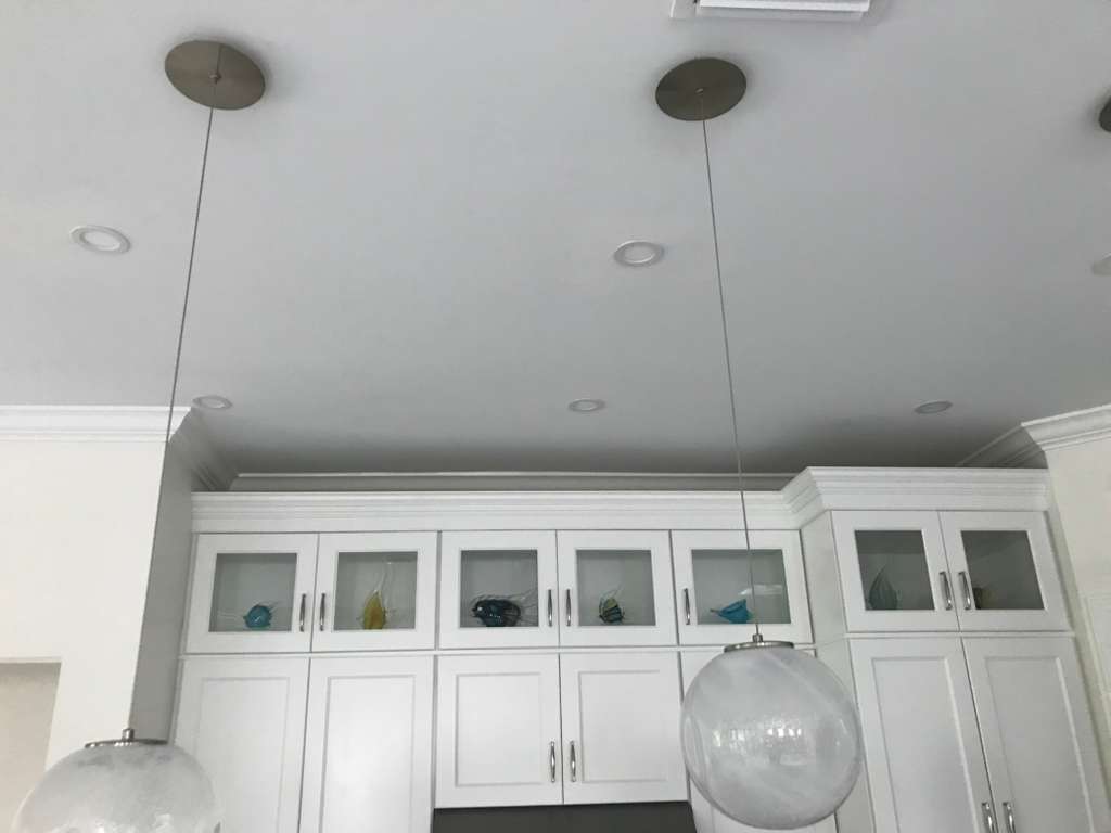 White cabinets with glass panel doors and pendant lighting