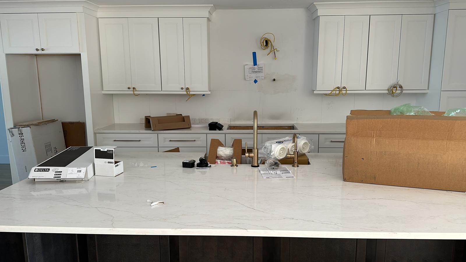 White kitchen cabinets with quartz island and gold fixtures