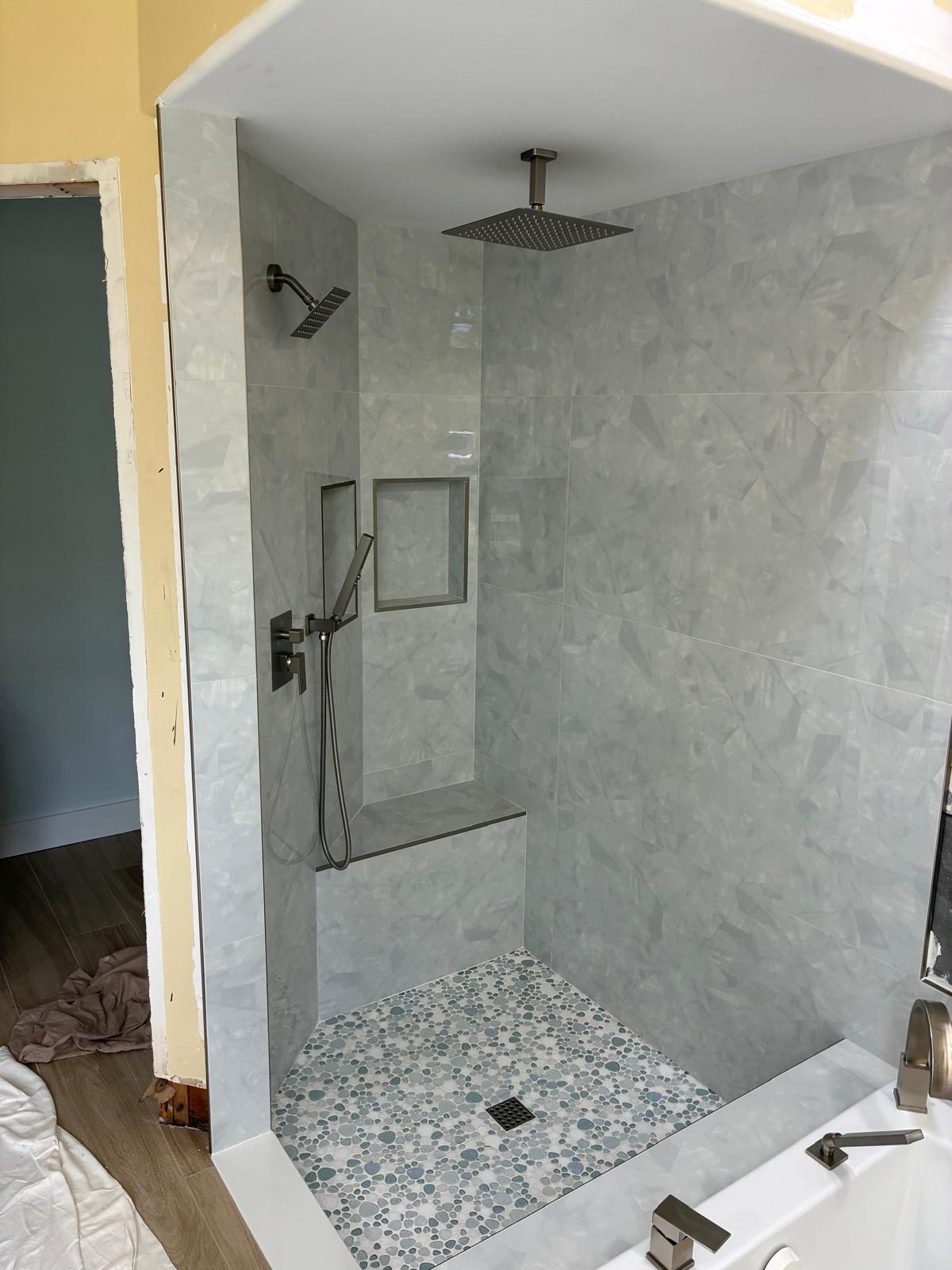 Curbless walk-in shower with marble tile, bench and pebble mosaic floor