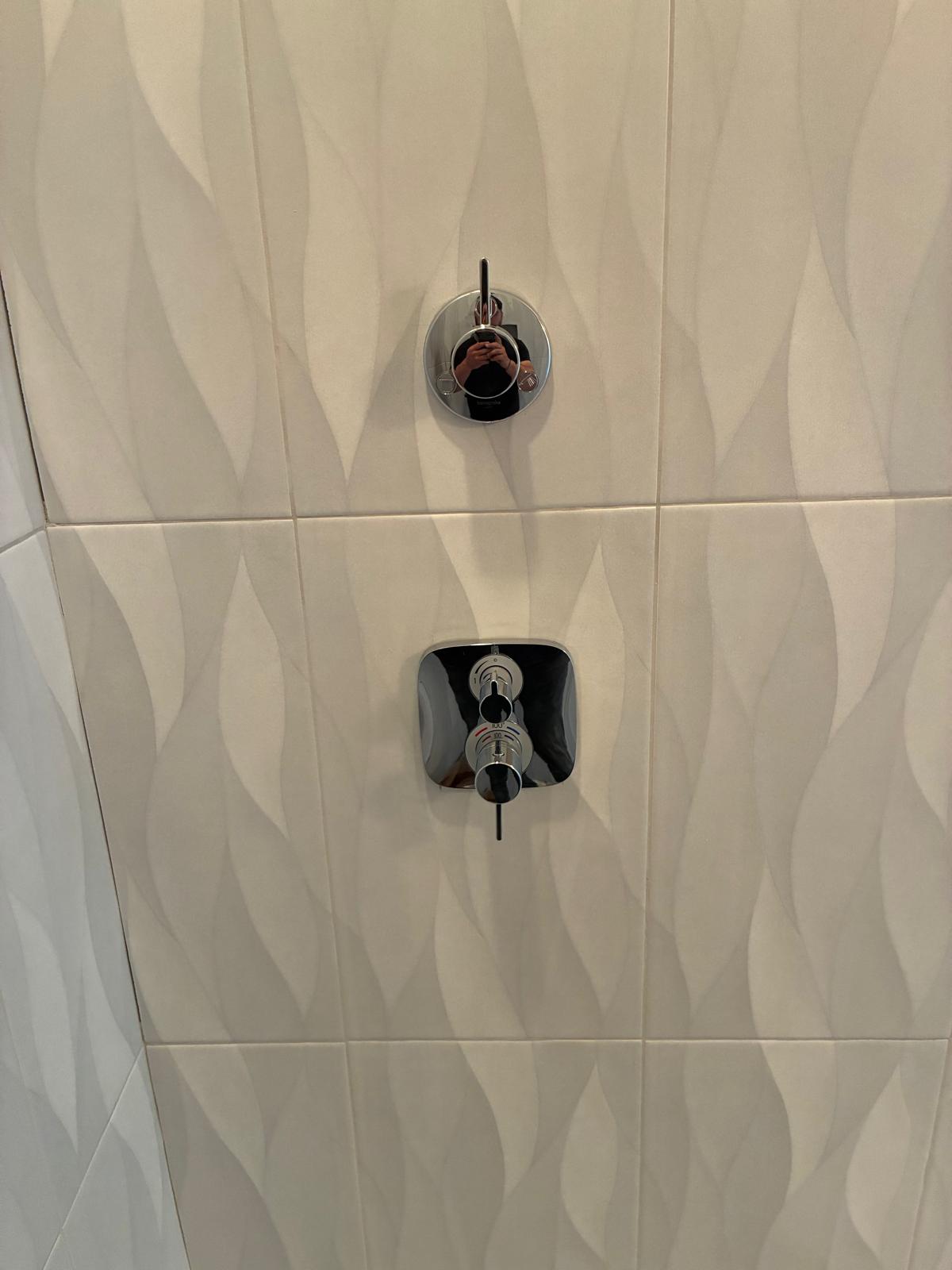 Chrome thermostatic shower valve installed on wave tile wall